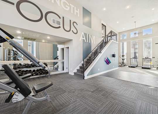 A gym with a staircase and a weight machine.