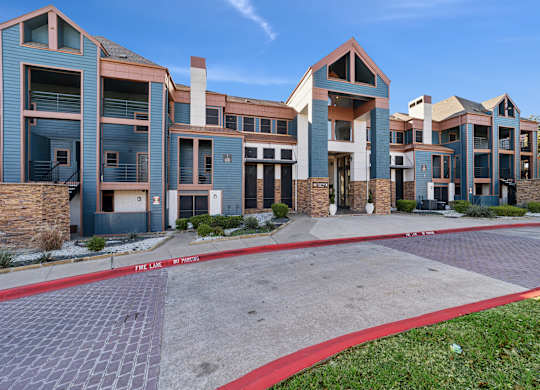 A row of modern buildings with a red brick pathway in front.