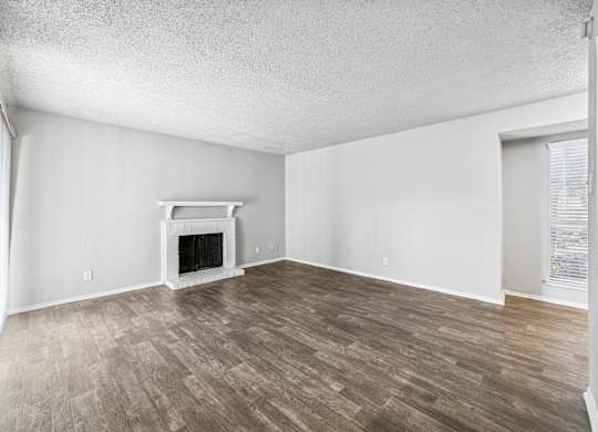 A room with a fireplace and wood flooring.