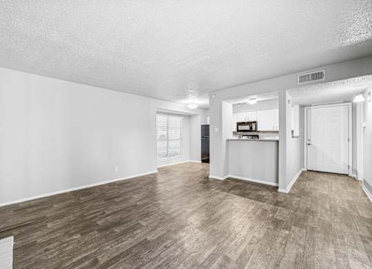 A spacious room with wooden flooring and white walls.