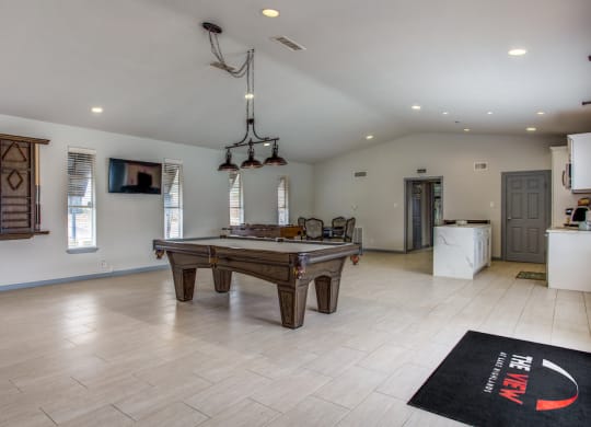 a large living room with a pool table and a kitchen