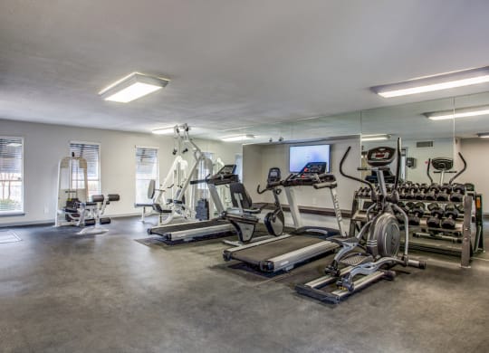 a spacious fitness room with cardio equipment and a flat screen tv
