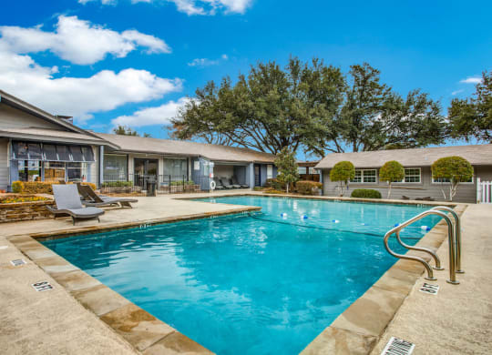 a swimming pool with lounge chairs and a house in the background