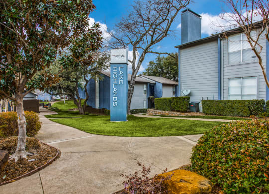 a sidewalk with a blue welcome sign in front of a house