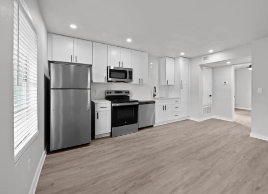 an empty kitchen with white cabinets and stainless steel appliances at Sunset Heights, Texas