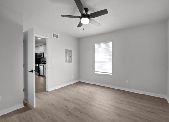 an empty living room with a ceiling fan and a door to a kitchen at Sunset Heights, San Antonio, TX