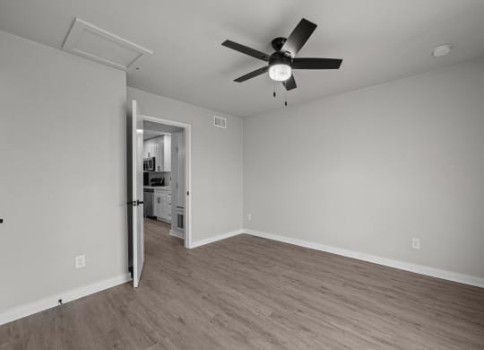 an empty living room with a ceiling fan and a door to a kitchen at Sunset Heights, San Antonio, TX