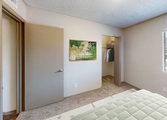 A bedroom with a bed, a painting, and a window.