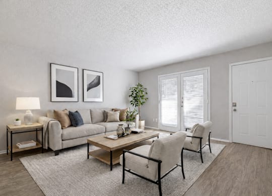 A living room with a grey couch, a coffee table, and two chairs.