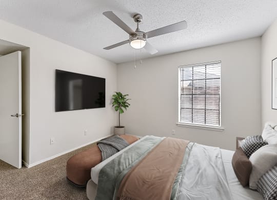 a bedroom with a ceiling fan and a flat screen tv