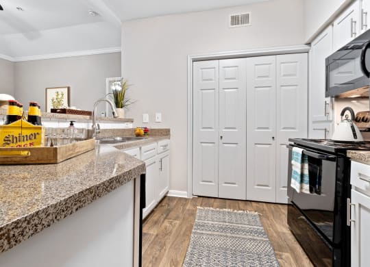a renovated kitchen with faux granite counter tops and black appliances at Fountains of Denton in Denton, TX