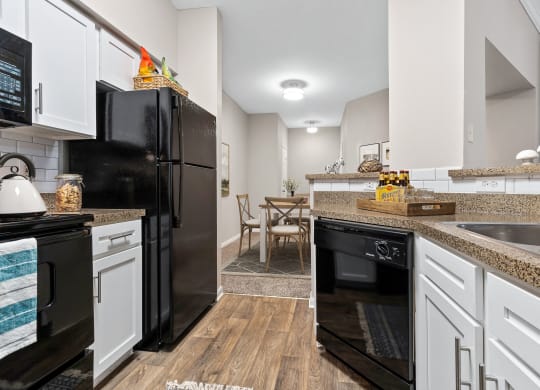 a renovated kitchen with black appliances and white cabinets at Fountains of Denton in Denton Texas