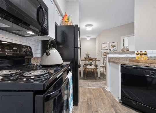a kitchen with black appliances and a stove and a refrigerator at Fountains of Denton in Denton, TX