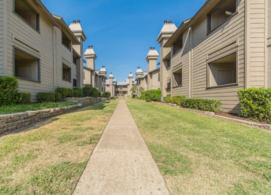a grassy path between apartment buildings