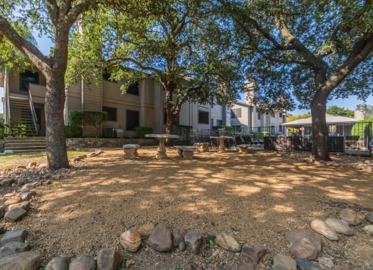 a picnic area with trees and rocks in front of a building