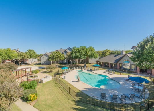 an aerial view of a swimming pool with patio furniture and resort style apartment buildings at Fountains of Denton in Denton, TX