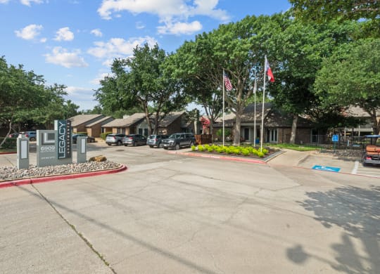 a parking lot with trees and buildings in the background