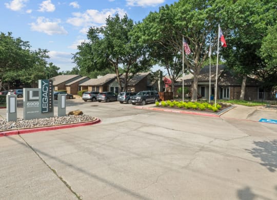 a parking lot with a sign and flags in front of a building