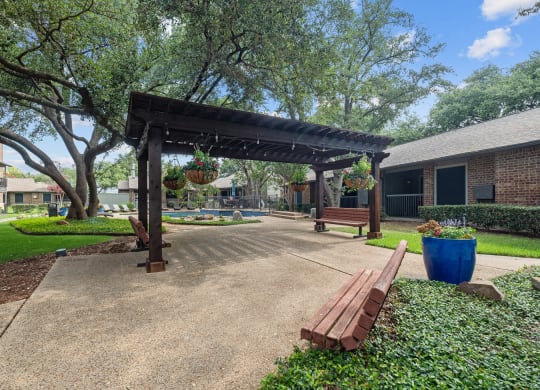 a park with a wooden bench and a pergola