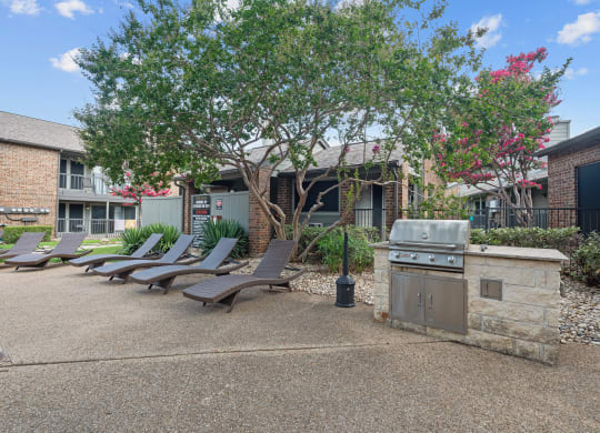 a barbecue and lounge chairs at legacy apartments in plano, tx
