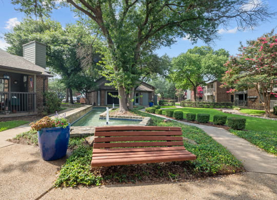a park with a bench and a pool in the background