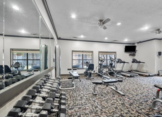 a spacious fitness center with cardio equipment and a flat screen tv