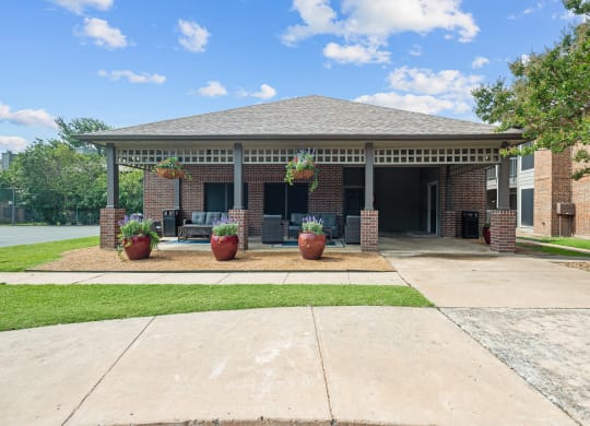 a covered patio with potted plants in front of a brick building