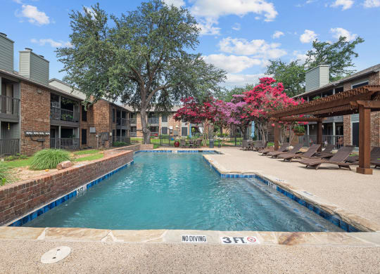 a swimming pool with lounge chairs and trees in the background