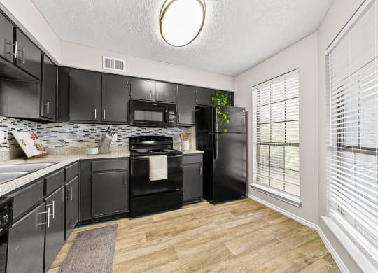 a kitchen with black cabinets and a large window