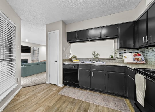 a kitchen with black cabinets and a sink and a window