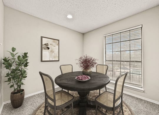 a dining room with a table and chairs and a window at Legacy Apartments in Plano, TX
