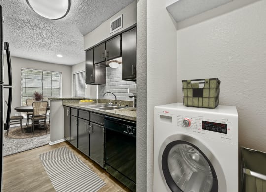a kitchen with a washing machine and a washer and dryer at Legacy Apartments in Plano, TX