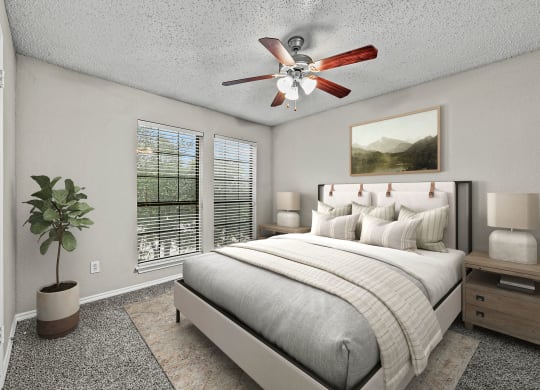 a bedroom with a bed and a ceiling fan at Legacy Apartments in Plano, TX