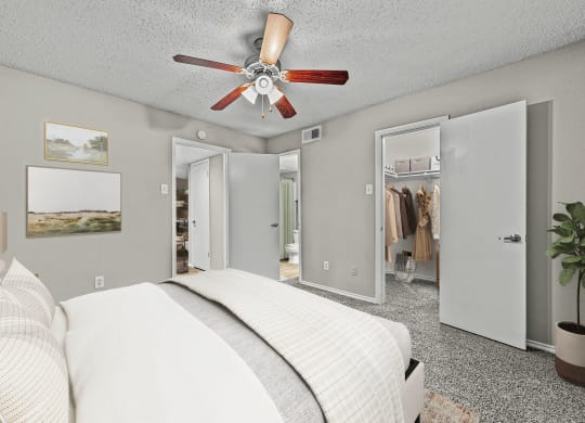 a bedroom with a bed and a ceiling fan at Legacy Apartments in Plano, TX
