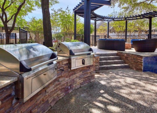 a patio with two bbq grills and a pergola