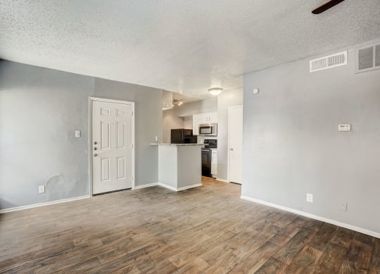 the living room and kitchen of an apartment with a hard wood floor