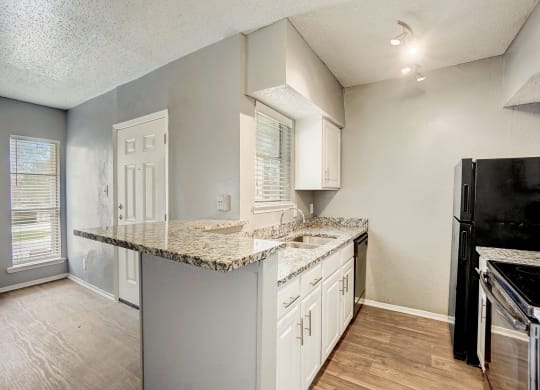 an empty kitchen with a granite counter top and white cabinets