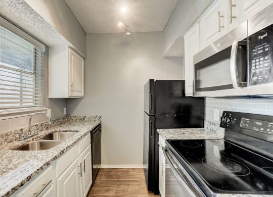 a kitchen with granite counter tops and black appliances