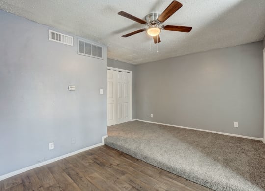 the spacious living room has a ceiling fan and a carpet