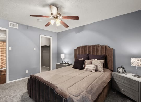 the master bedroom has a king sized bed and a ceiling fan