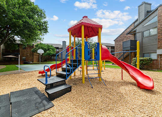 A playground with a red slide and a yellow and blue structure.