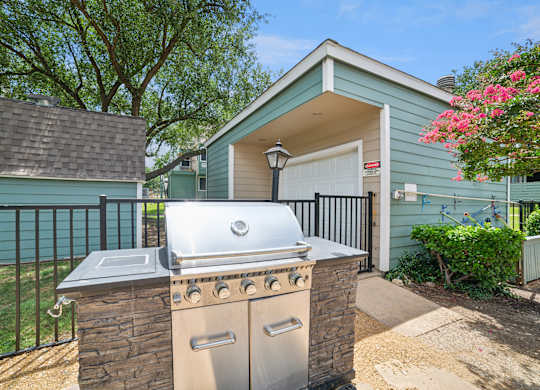 A house with a blue exterior has a silver grill on a stone pillar.