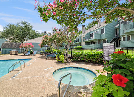 A pool surrounded by a green fence and flowers.