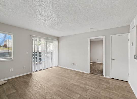A spacious room with a sliding glass door and a wooden floor.