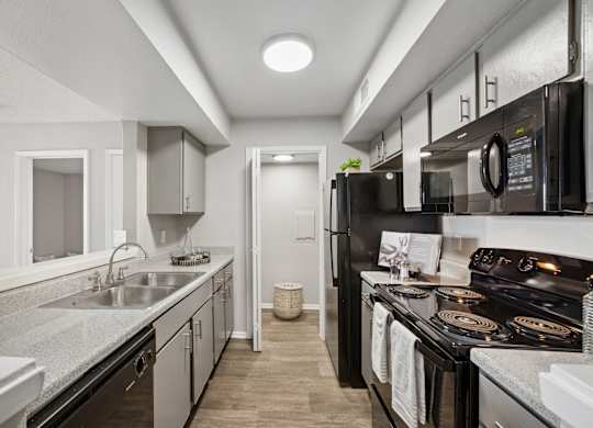 A modern kitchen with black appliances and white cabinetry.