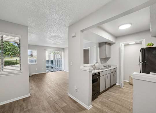 A kitchen with white cabinets and a black fridge.