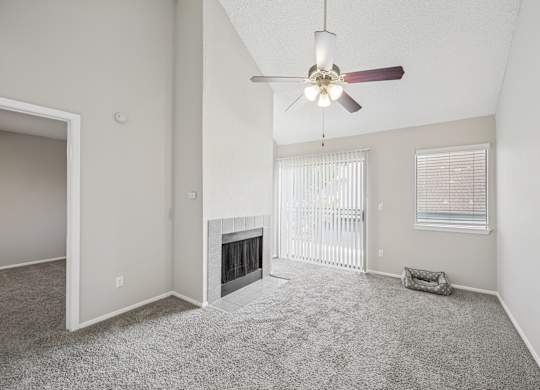 A spacious living room with a fireplace and a ceiling fan.