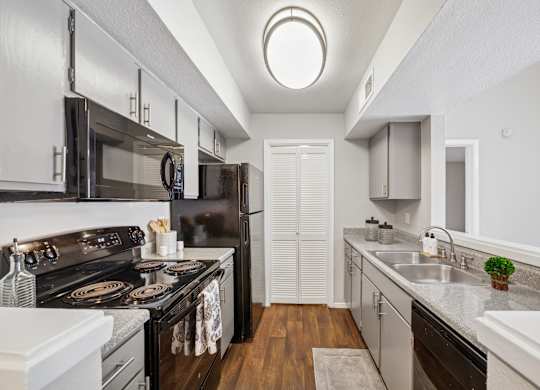 A modern kitchen with black appliances and white cabinets.