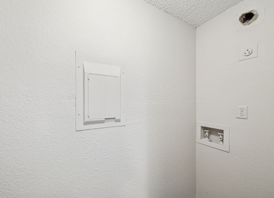 A white wall with a white electrical outlet and a white door.