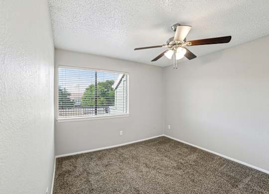 A room with a ceiling fan and a window with blinds.